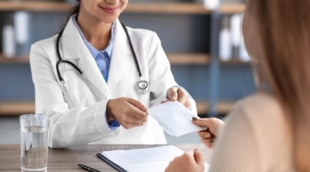 Happy glad young hindu lady doctor therapist in white coat take money in clinic office interior. Bribe, illegal procedure, health care, corruption, business, problems in medicine, cropped, free space